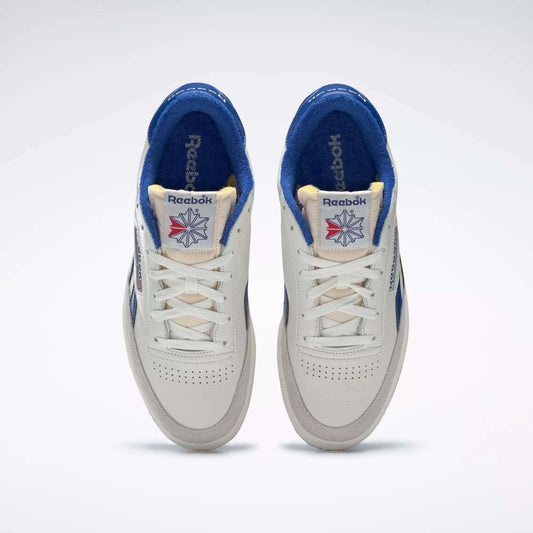 A pair of Reebok Men's Club C Revenge Vintage Shoes in white with blue accents, seen from above. These tennis-inspired sneakers have cream tongues, perforated toes, and tongue labels featuring the Reebok logo with a red and blue starburst.
