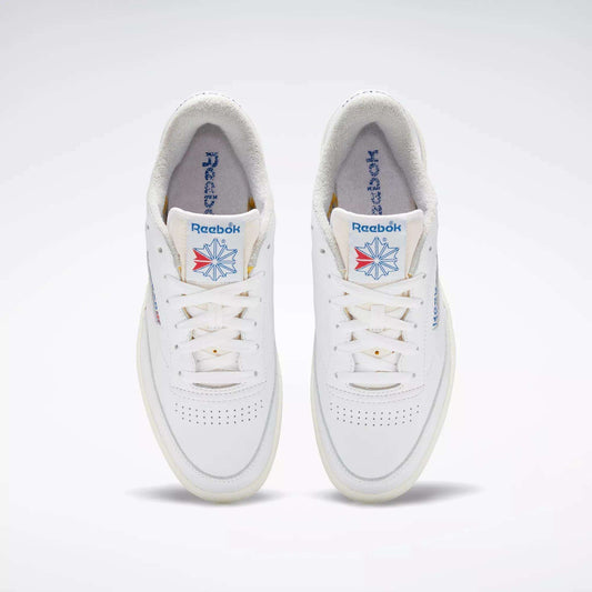 A pair of Reebok Club C 85 Vintage Shoes in white, seen from above, with blue and red branding on the tongues, a leather upper with subtle perforations on the toes, set against a light gray background.