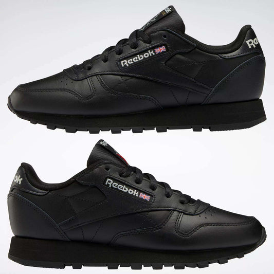 Two black Reebok Women's Classic Leather Shoes are shown in side view, one above the other, on a white background. The cushioned midsole, Reebok logo, and Union Jack flag appear on the sides and heel.