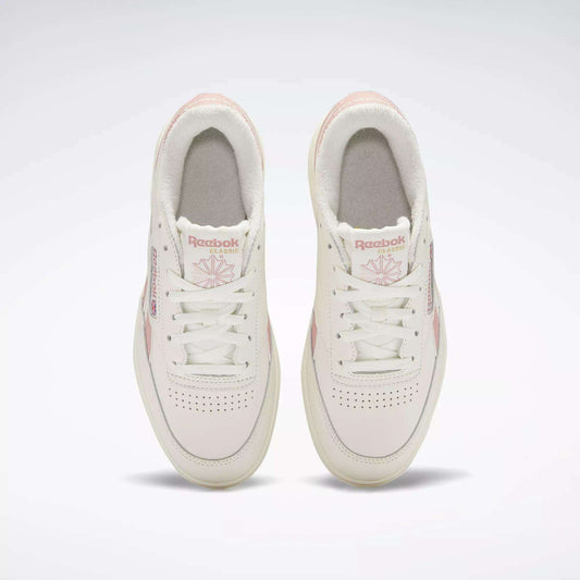 Top view of a pair of Reebok Women's Club C Double Revenge Shoes in white with light pink accents and laces, featuring the Reebok logo and design details on the tongues and sides, set against a plain white background.
