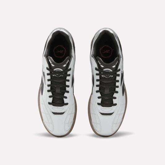 Top view of Reebok Hammer Street Shoes—soccer-inspired full-grain leather shoes with black laces, brown soles, and a pink logo on the black insole—placed side by side on a light background.