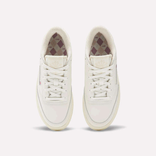 The Reebok Women's Club C Golf Shoes are white, spikeless, lace-up golf shoes with a water-resistant leather upper, minimalist design, and a subtle checkered inner lining.