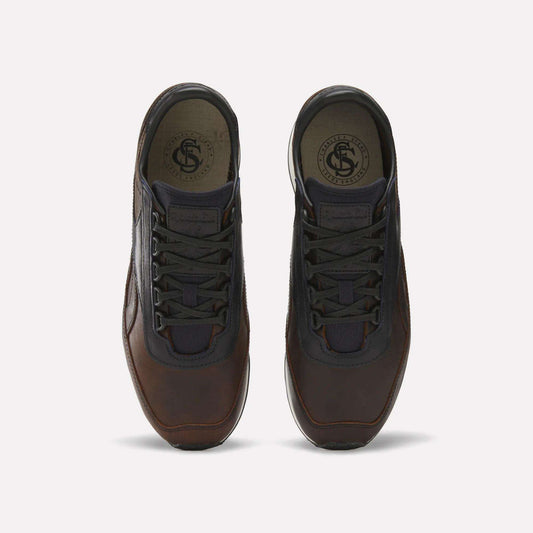 The Reebok Camargue x C.F. Stead Shoes feature brown full-grain leather, black laces, and dark mesh accents, shown from above on a plain light background.