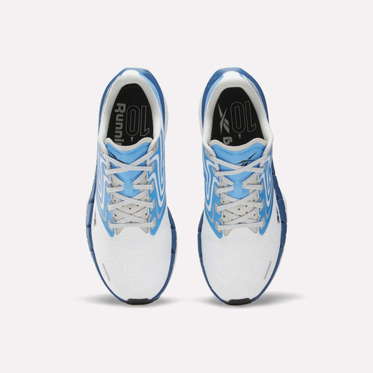 Top view of Reebok Men's FloatZig Tread Running Shoes in white with blue accents, dual-density midsole, blue soles, white laces, and black insoles marked "Running," placed side by side on a light background.