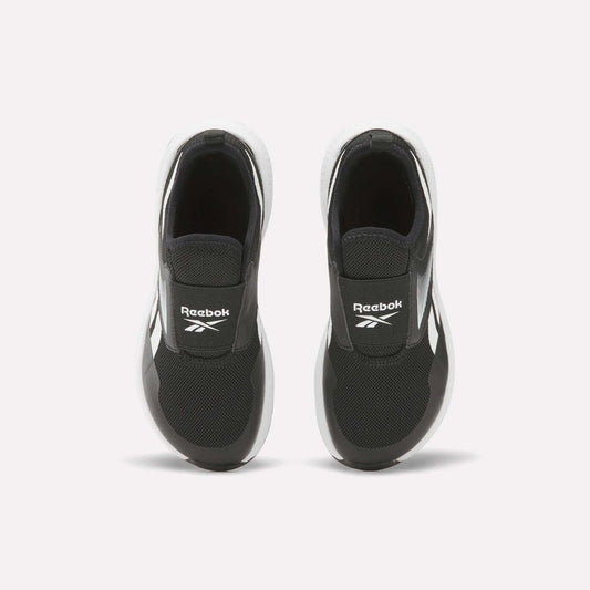 A pair of Reebok Nano Play Slip-On Shoes for little kids in black with white soles, seen from above. The shoes feature the Reebok logo on the tongue and are placed side by side on a plain white background.