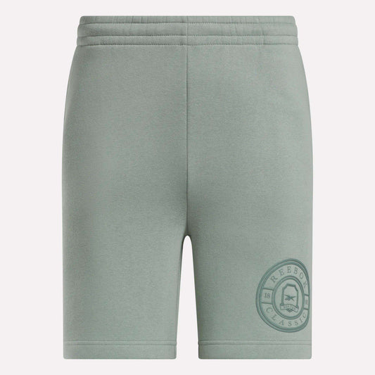 Light green Men's Crest Shorts by Reebok featuring a relaxed fit, elastic waistband, soft cotton fabric, and a darker green circular Reebok Classic logo near the left hem. Front view shown.