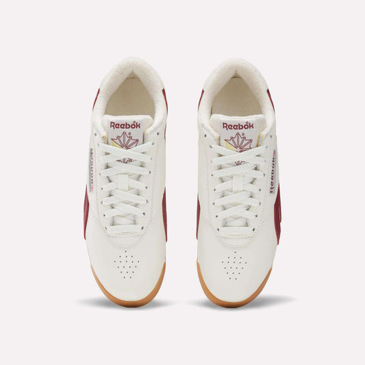 Top view of Women's Freestyle Lo Shoes by Reebok in white with maroon accents, gum soles, and logo with red maple leaf on the tongue. These women's retro sneakers are neatly laced and set side by side on a light background.