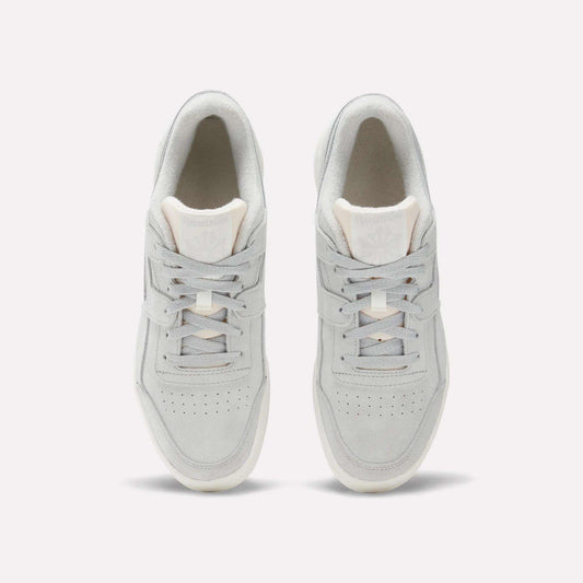 Top view of Reebok Workout Plus Shoes in light gray with white soles, laces, and subtle branding on the tongue. These classic sneakers channel authentic '80s fitness style and are shown side by side on a plain white background.