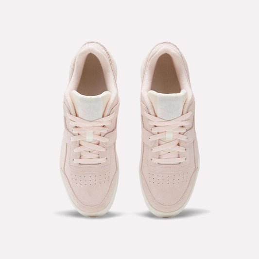 The Reebok Workout Plus Shoes are shown from above on a white background, featuring light pink suede, laces, and toe box perforations that blend classic ’80s fitness style with modern comfort.