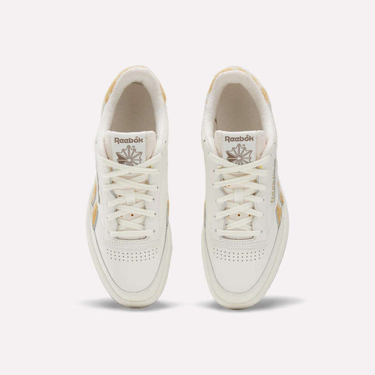 Top view of a pair of Reebok Club C Revenge Vintage Shoes with beige accents, white laces, and perforated detailing on the toes, featuring a classic leather upper. These tennis-inspired sneakers are displayed on a plain light background.