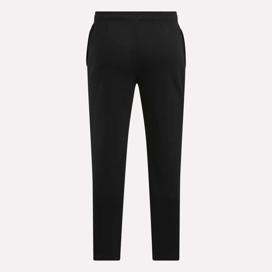 Men's Patent Pants by Reebok in black, featuring a slim fit, elastic waistband, and tapered legs, shown from the back against a plain light background.