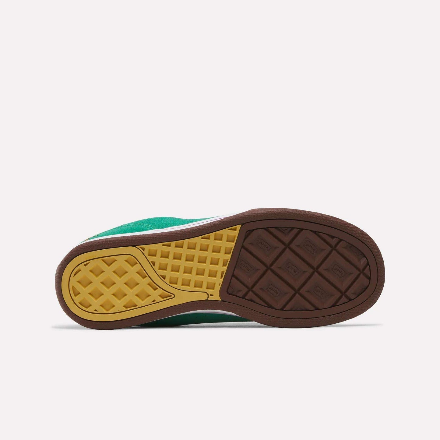 The image shows the sole of the Reebok x BBC Board Flip Skate Shoes with a brown and yellow geometric pattern and textured grips, while part of the green upper is visible. Brand: Reebok.
