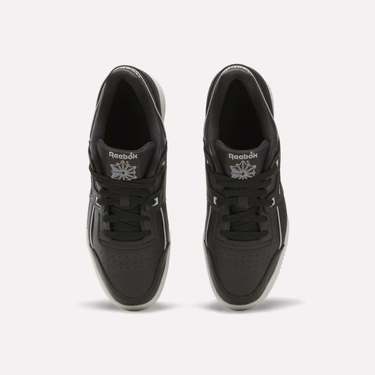 Top view of a pair of black Reebok Workout Plus Shoes with black laces, white accents, and the Reebok logo in white on each tongue. These sneakers are placed side by side on a plain white background.