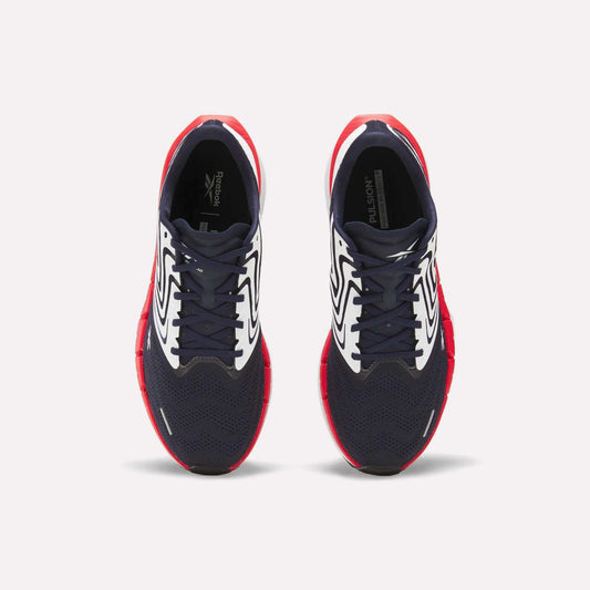 The Reebok Men's FloatZig Tread Running Shoes feature navy blue mesh toes, white patterned sides, and bright red soles—ideal for treadmill workouts. Shown from above against a plain white background.