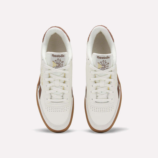 Top view of a pair of Men's Club C Revenge Vintage Shoes by Reebok, in white leather with brown soles and accents, showcasing the Reebok logo and starburst design on the tongue against a plain light background.