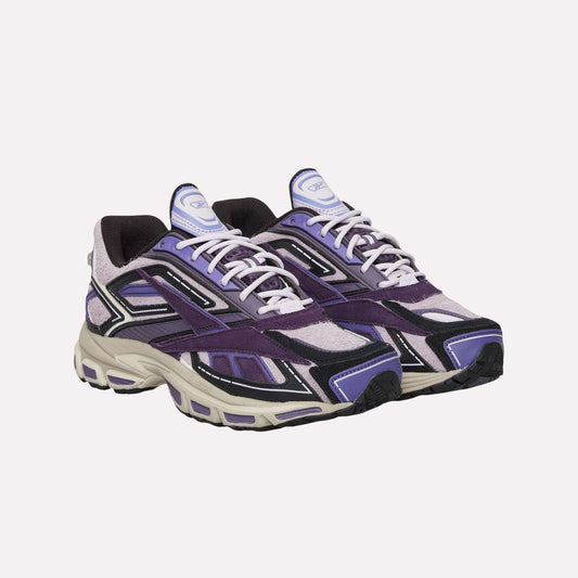 The image shows the Reebok Premier Road Ultra Shoes, featuring purple, black, and white suede and mesh uppers, white laces, and chunky beige dual-density soles. Both side and front views are displayed.
