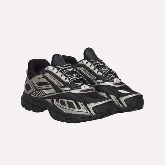 A pair of Reebok Premier Road Ultra Shoes in black and silver, featuring a chunky sole, mesh panels, dual-density midsole, and patterned overlays, displayed side by side angled slightly to the right.