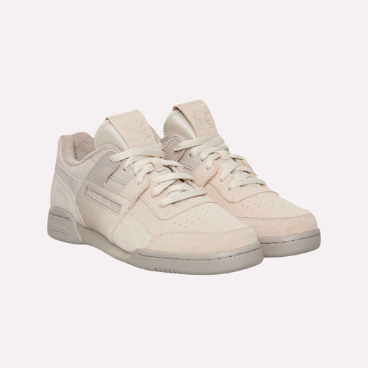 A pair of Reebok Workout Plus Og Shoes in light beige with suede uppers and light gray soles, showcasing a classic silhouette, displayed on a plain light blue background.
