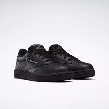 A pair of black Reebok Kids' Club C Shoes for little kids with laces, leather upper, Reebok branding, and Union Jack flag on the side are displayed on a light background.