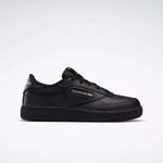 The Kids' Club C Shoes - Little Kids by Reebok are black low-top sneakers with a leather upper, Reebok logo and British flag on the side, black laces, and a black rubber sole, shown against a plain light gray background.