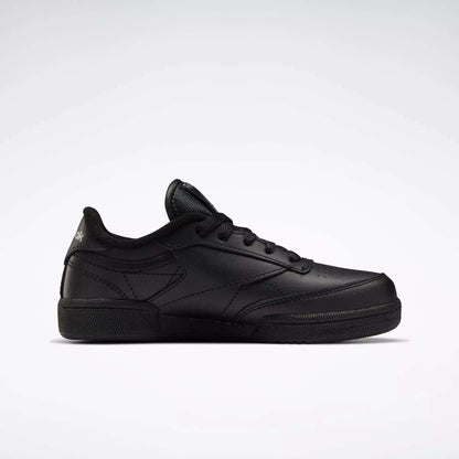 The Reebok Kids' Club C Shoes - Little Kids feature a black leather upper, black laces, subtle stitching details, and a simple low-top design, displayed on a plain white background.