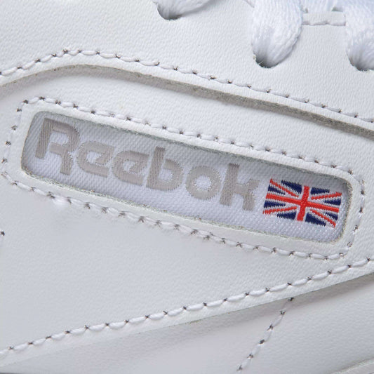 Close-up of Reebok Women's Club C 85 Shoes in white, highlighting the Reebok logo and a small Union Jack flag on the side, detailed stitching, and part of the white shoelaces at the top.