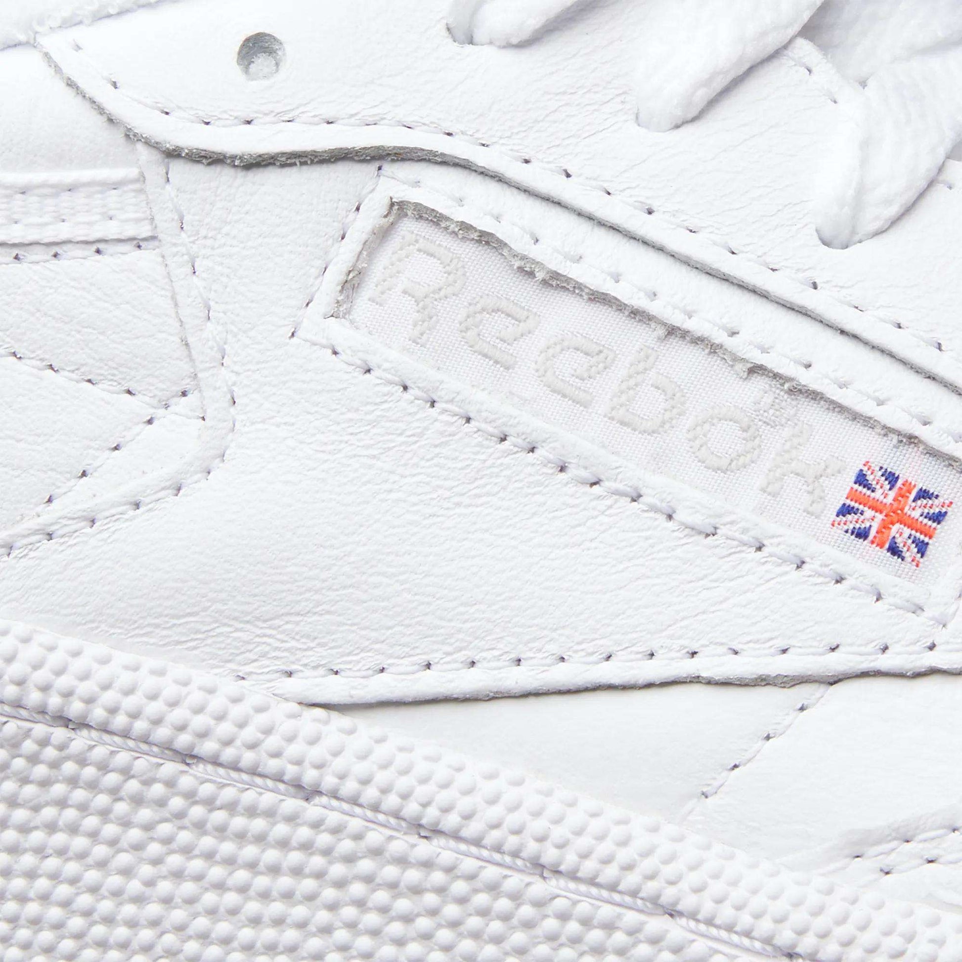 Close-up of the Reebok Women's Club C 85 Shoes highlights the logo, a small UK flag patch, and detailed leather stitching—making these sneakers a timeless choice.