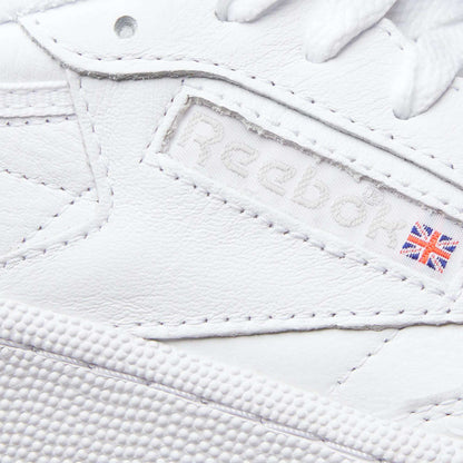 Close-up of the Reebok Women's Club C 85 Shoes highlights the logo, a small UK flag patch, and detailed leather stitching—making these sneakers a timeless choice.