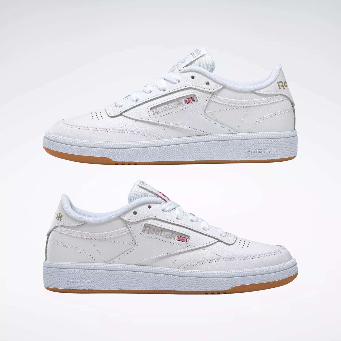 A pair of Reebok Women's Club C 85 Shoes in white with gum soles, side by side, showcasing the Reebok logo and UK flag—classic women's sneakers displayed against a plain white background.