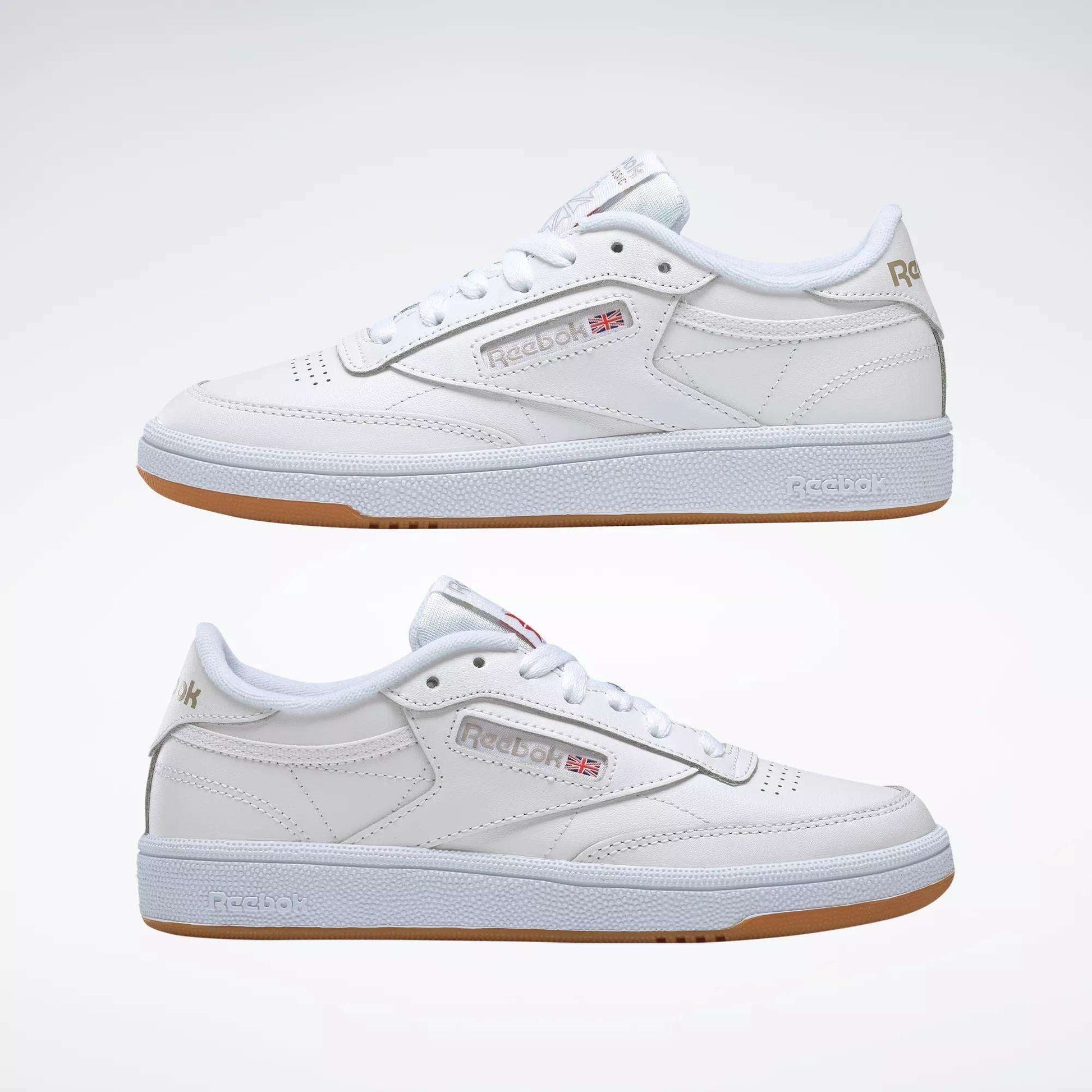 A pair of Reebok Women's Club C 85 Shoes in white with gum soles, side by side, showcasing the Reebok logo and UK flag—classic women's sneakers displayed against a plain white background.