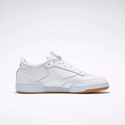 The Reebok Women's Club C 85 Shoes are white low-tops with a gum sole and subtle stitching, shown in side profile against a plain light background.
