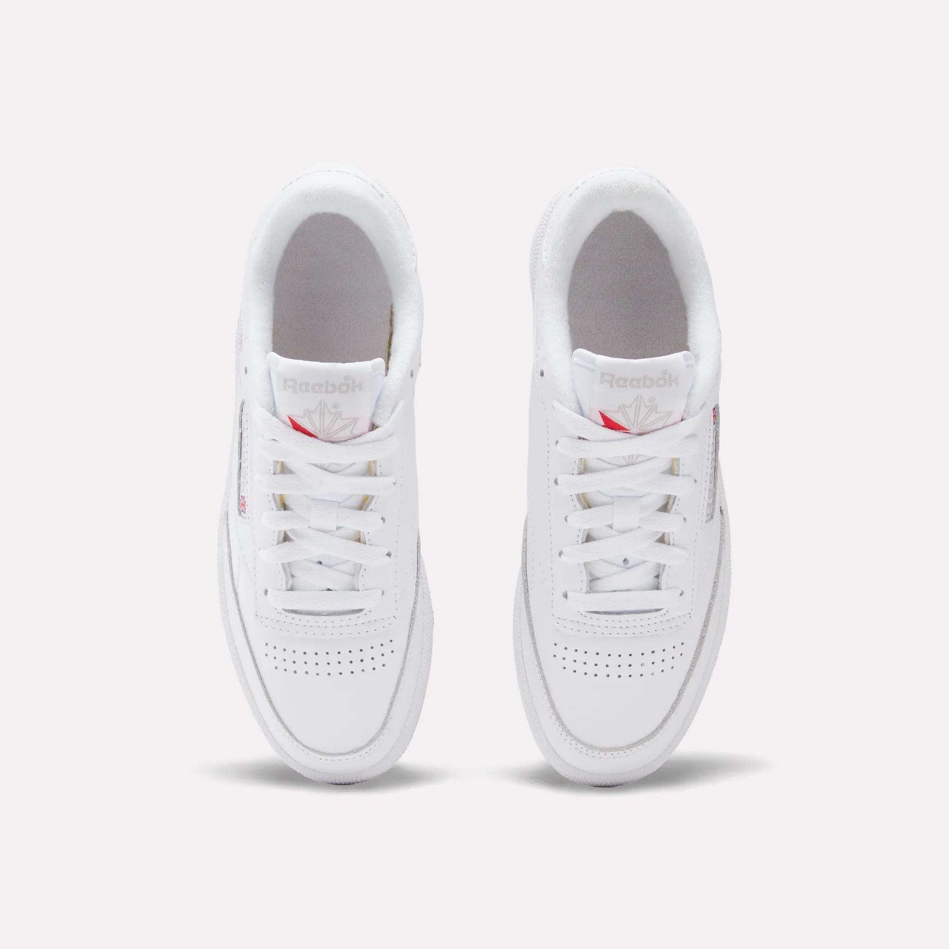 A pair of Reebok Women's Club C 85 Shoes are shown from above on a white background, highlighting their laces, perforated toe area, and the Reebok logo on the tongue.