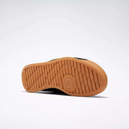 The image shows the sole of Reebok Women's Princess Shoes against a light gray background. The light brown sole features a textured, grippy pattern with a circular design near the ball of the foot and the Reebok logo by the heel.