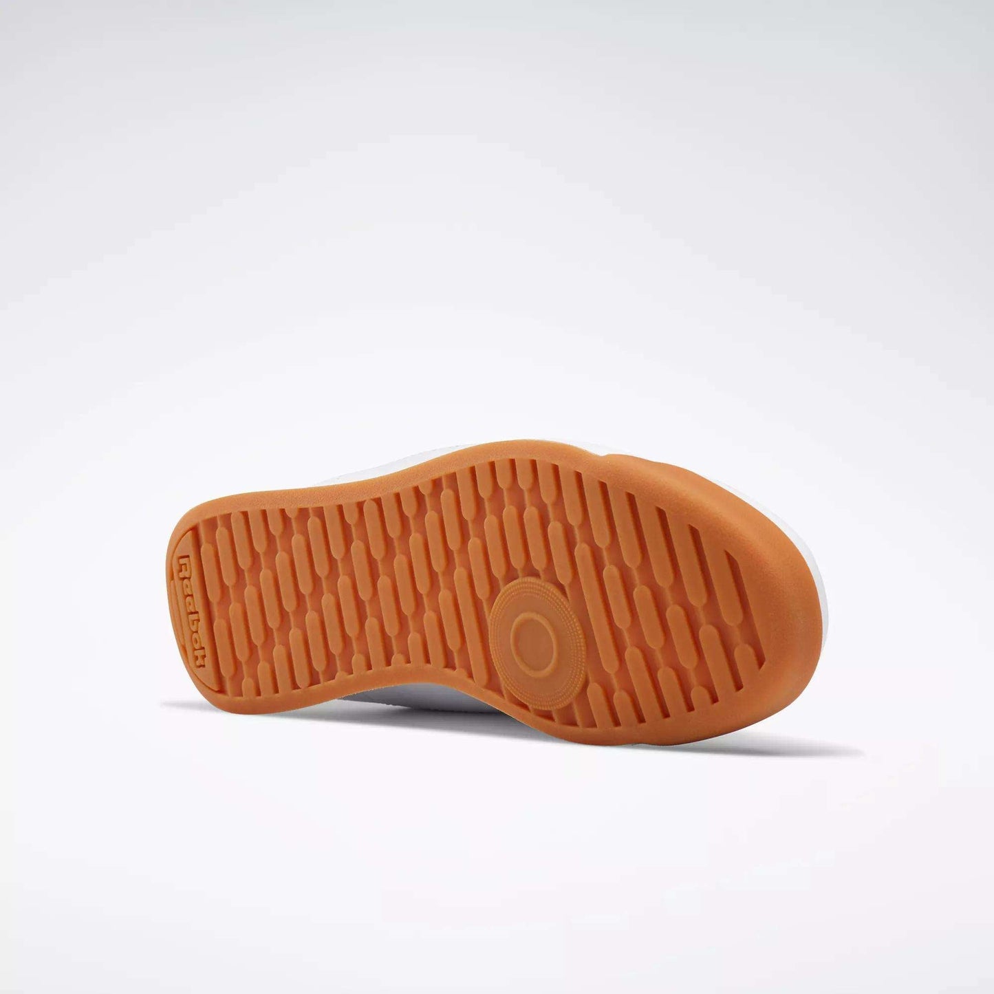 A Reebok Women's Princess Shoe rests on its side, displaying the textured orange rubber sole with Reebok branding and a circular grip pattern for extra cushion against a plain light background.