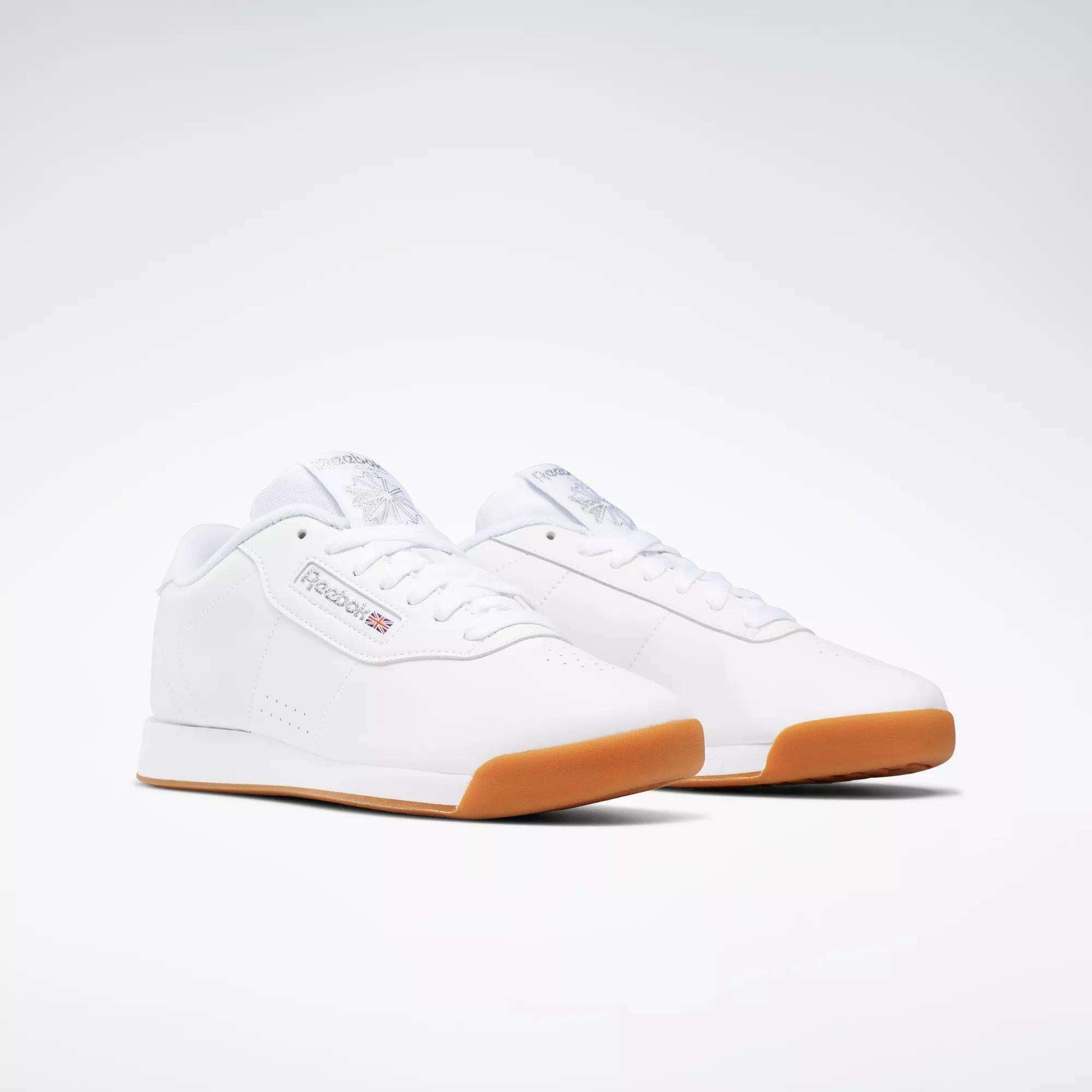 Reebok Women's Princess Shoes in classic white with gum rubber soles, shown on a white background. Featuring subtle Reebok logos, these shoes deliver timeless style and superior cushioning for all-day comfort.