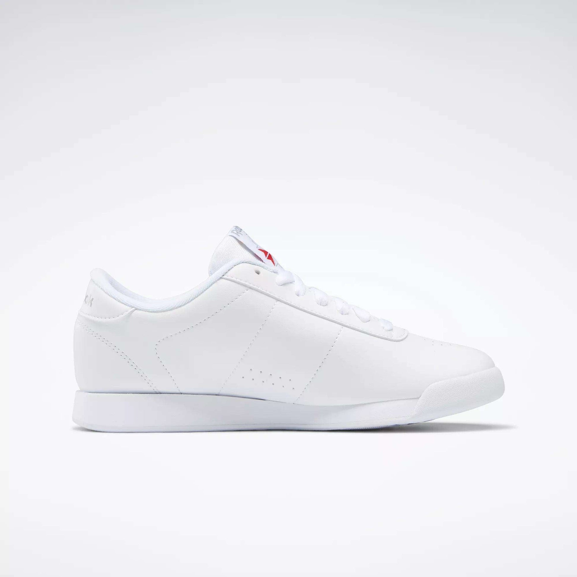 The Reebok Women's Princess Shoes feature a minimalist white design with subtle stitching and white laces, offering timeless heritage style. Shown from the side on a plain white background.