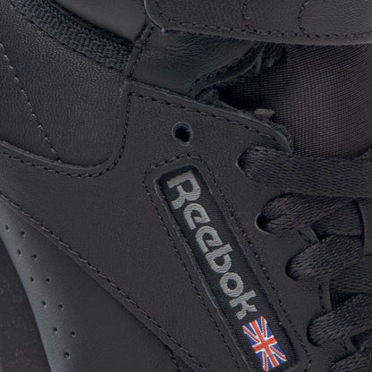 Close-up of the Reebok Women's Freestyle Hi Shoes, a black high-top sneaker with black laces, detailed stitching, and the Reebok logo plus Union Jack flag on the side—ideal for women’s fitness enthusiasts.