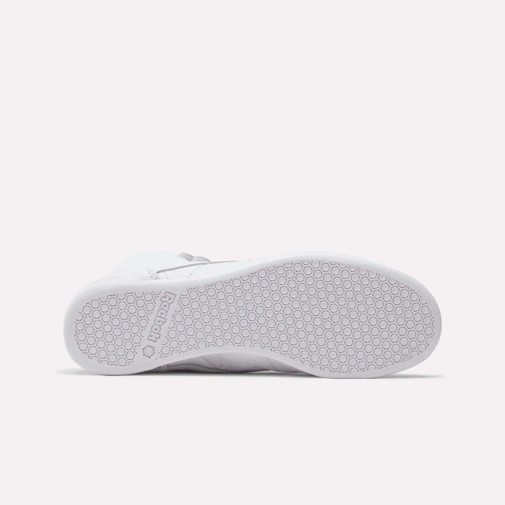 The Reebok Women's Freestyle Hi Shoes feature a white textured rubber sole with a hexagonal pattern, embossed Reebok logo near the heel, and are perfect for fitness enthusiasts who love stylish high tops.