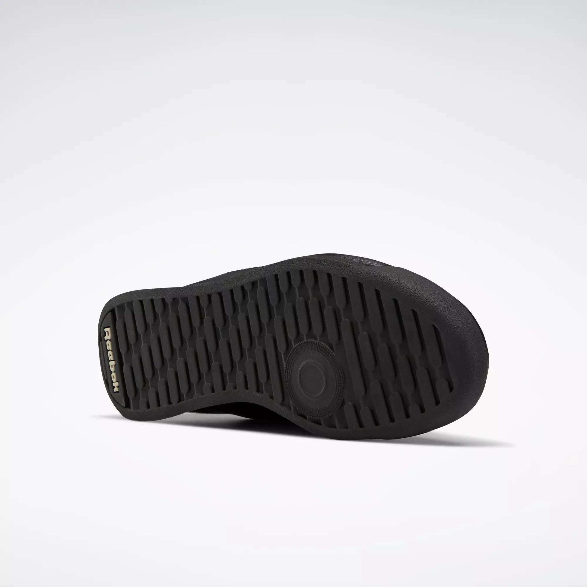 The image shows the black rubber sole of the Reebok Women's Princess Wide Shoes, lying on its side against a white background. The textured sole pattern offers grip, and the Reebok logo appears near the heel.