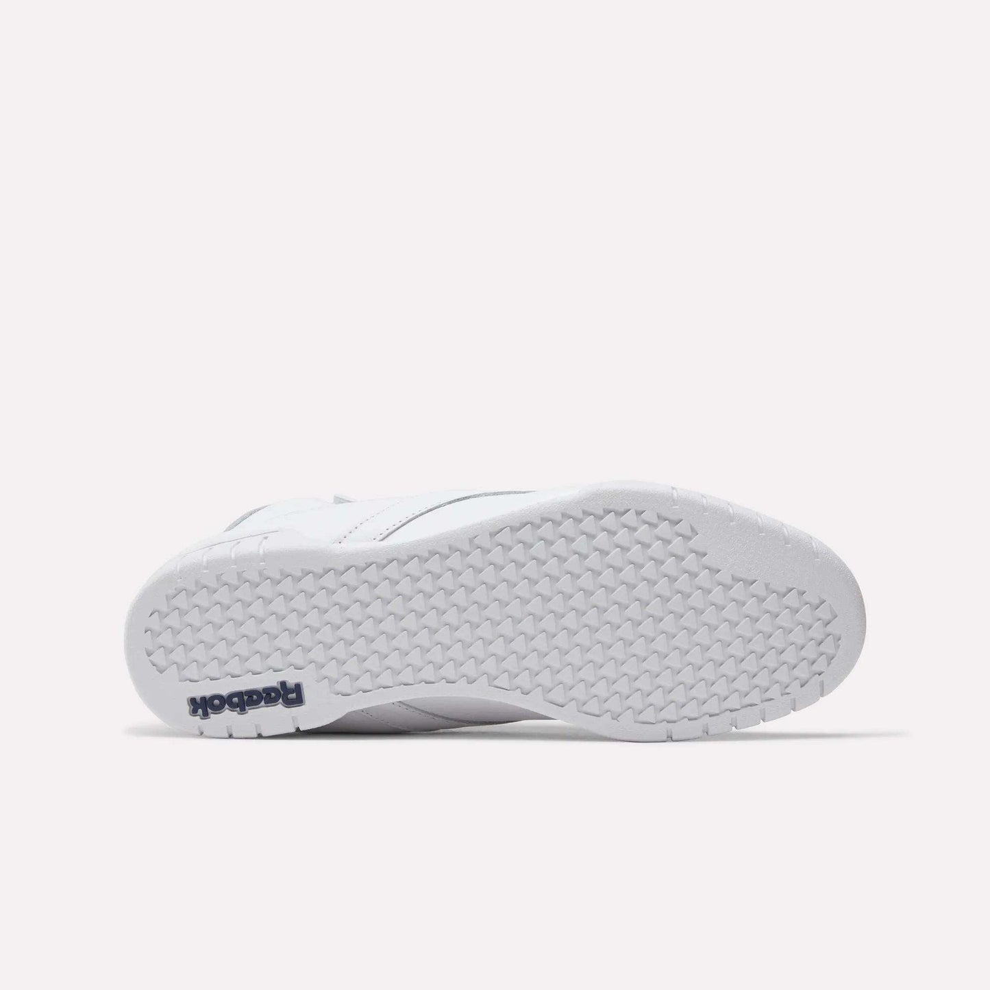 The image shows the bottom view of a white Reebok Men's EX-O-FIT Hi Shoe with a textured rubber sole. "Reebok" in navy blue appears on the heel, highlighting its classic old-school style.