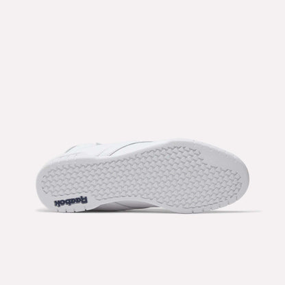 The image shows the bottom view of a white Reebok Men's EX-O-FIT Hi Shoe with a textured rubber sole. "Reebok" in navy blue appears on the heel, highlighting its classic old-school style.
