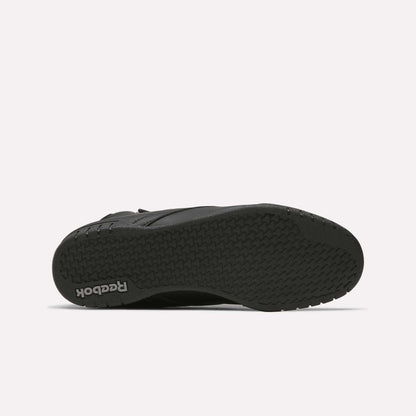 The image displays the black rubber sole of a Reebok Men's EX-O-FIT Hi Shoe, seen from beneath. It showcases a herringbone tread pattern and the Reebok logo near the heel, highlighting its retro-inspired design.