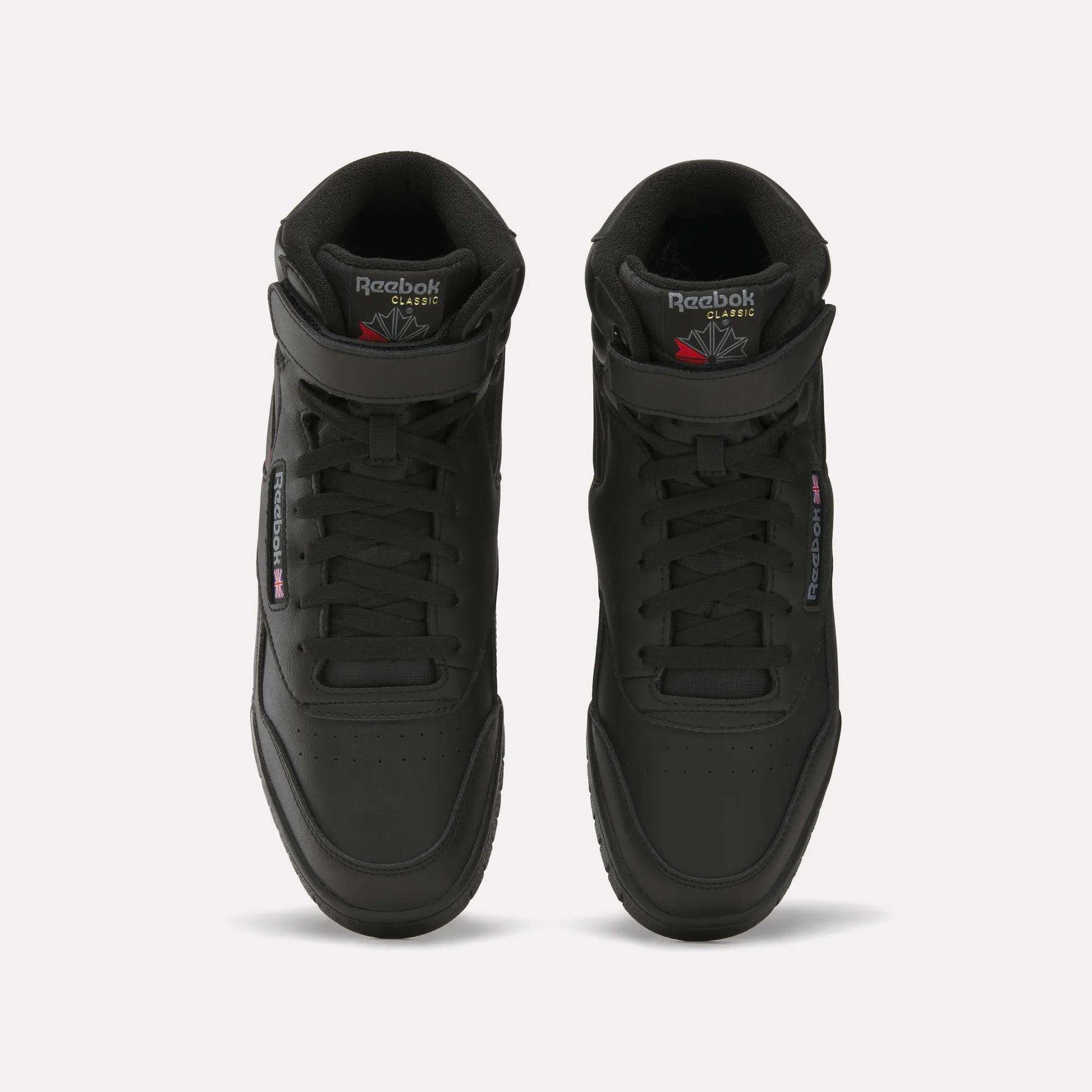 A pair of black Reebok Men's EX-O-FIT Hi shoes with an old-school design, viewed from above, featuring perforated toes, laces, and Reebok branding on the tongues and sides.