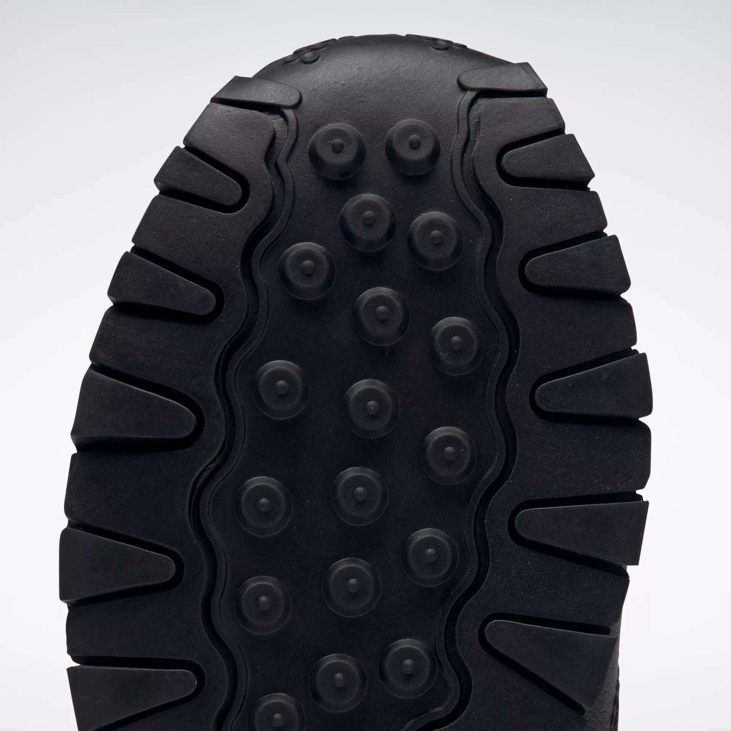 Close-up of the black sole on Reebok Kids' Classic Leather Shoes - Preschool, showing thick, rugged treads and circular indents for traction and durability, plus lightweight cushioning for all-day comfort.