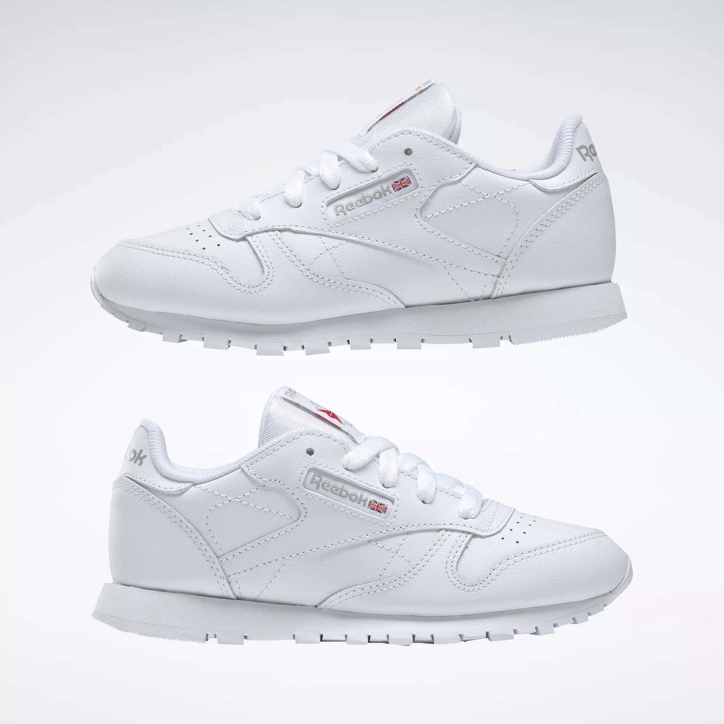 The Reebok Kids' Classic Leather Shoes - Preschool feature a white leather upper, white laces, grey soles, and subtle side and heel branding, shown on a plain white background.