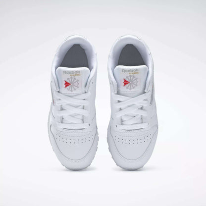 Top view of Reebok Kids' Classic Leather Shoes - Preschool, featuring a white leather upper, white laces, perforated toe boxes, and Reebok logos on the tongues against a plain white background.