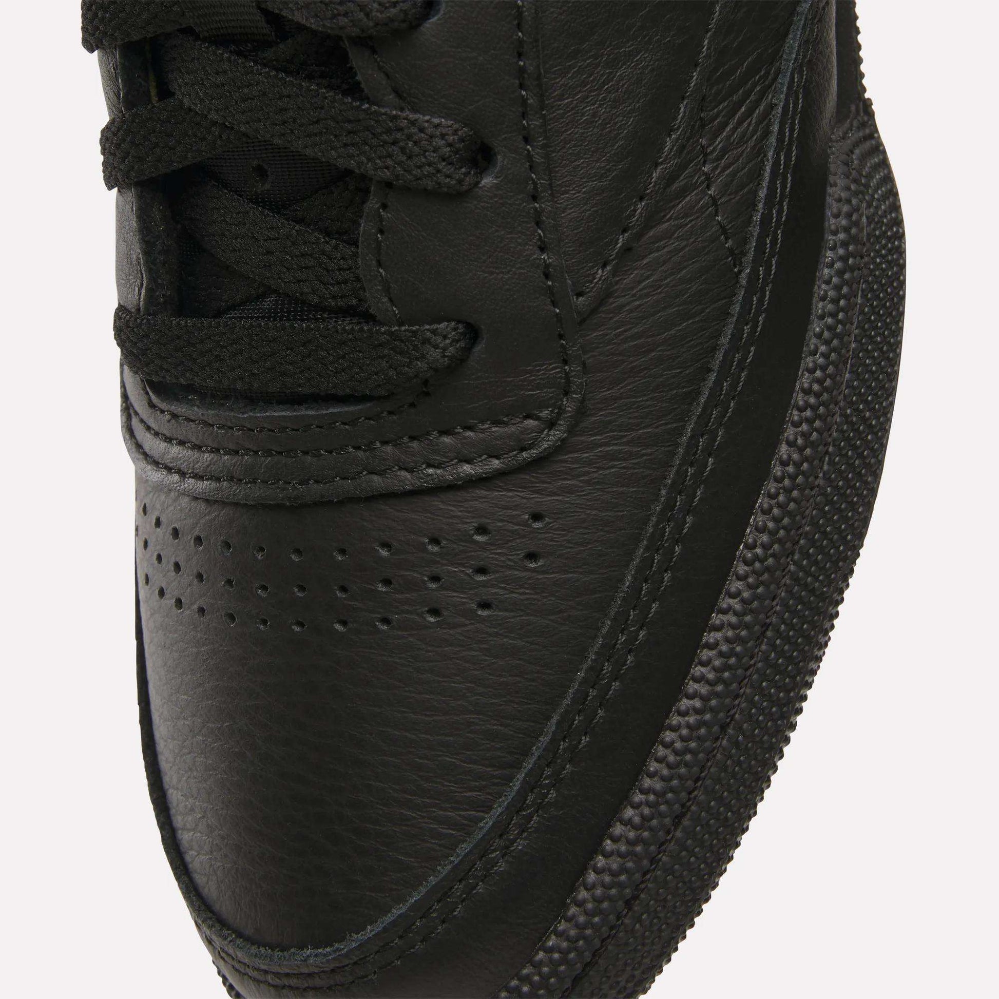 Close-up of the toe area of Reebok Club C 85 Shoes, featuring black leather, black laces, a textured rubber sole, visible stitching details, and small perforations on the upper.