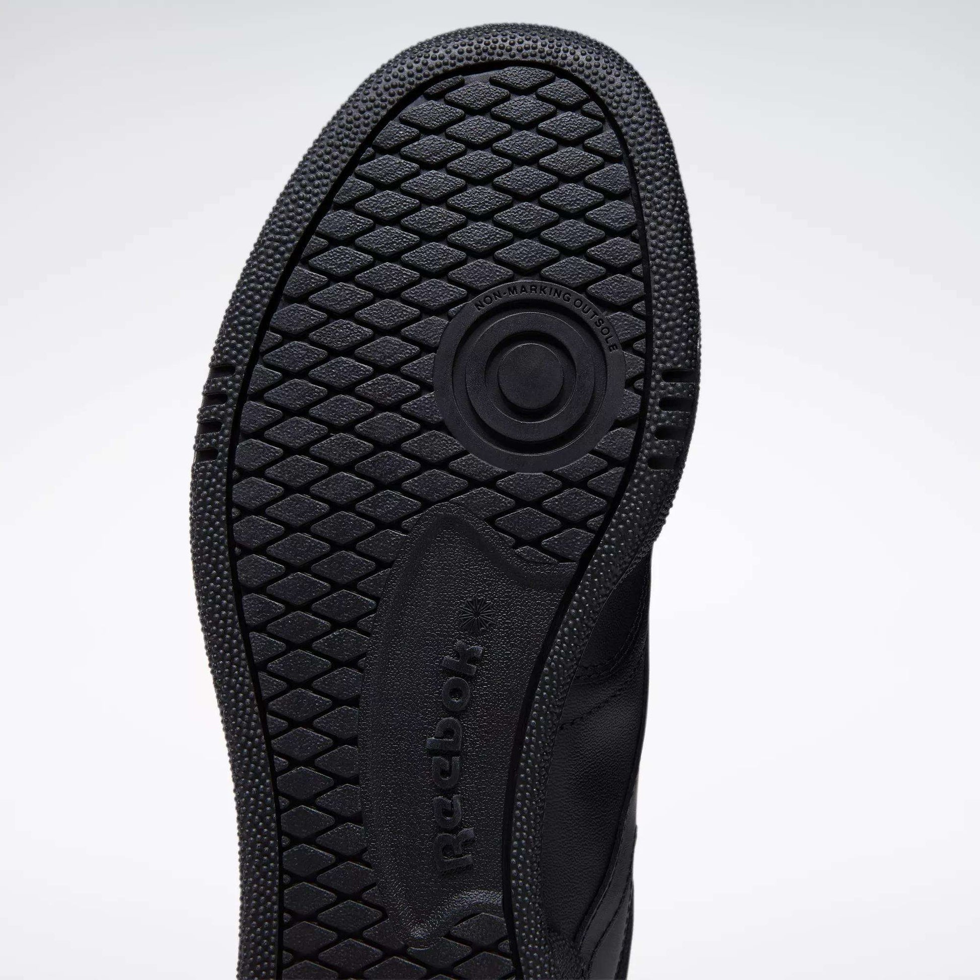 Close-up of the black rubber sole on the Reebok Club C 85 Shoes, featuring a textured hexagonal tread and circular groove, with visible Reebok branding—highlighting its tennis-inspired design.
