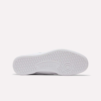 The bottom view of the white Reebok Club C 85 Shoes shows a zigzag tread pattern, a circular grip by the toe, and an embossed Reebok logo in the center, highlighting these classic leather sneakers.