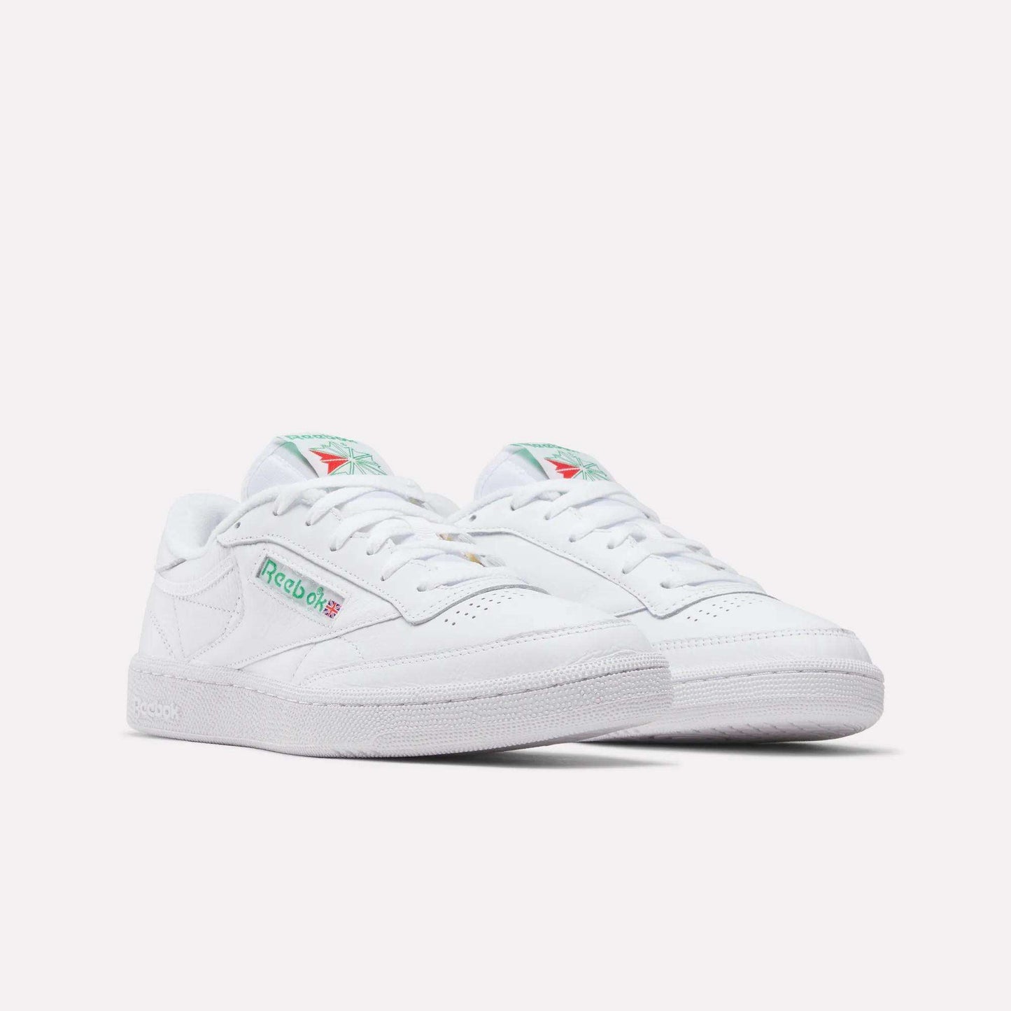 A pair of Reebok Club C 85 Shoes in white leather with green and red logo accents, shown on a plain white background. These tennis-inspired sneakers have a classic low-top design and perforated toe detailing.
